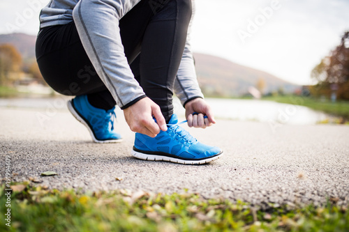 Unrecognizable young runner tying shoelaces.