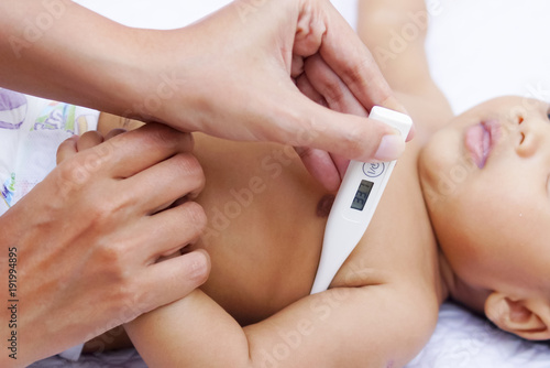 Mother Measures The Temperature Of Her Baby Using Digital Thermometer 