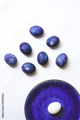 Stylish background of ulta violet Easter eggs and plate isolated on white. Dyed Easter eggs