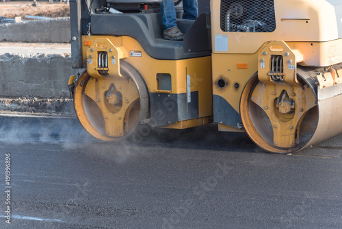 Fototapeta Naklejka Na Ścianę i Meble -  Side view small yellow ride on roller asphalt compactor aligns the road. Laying new asphalt. Vibration roller compactor.