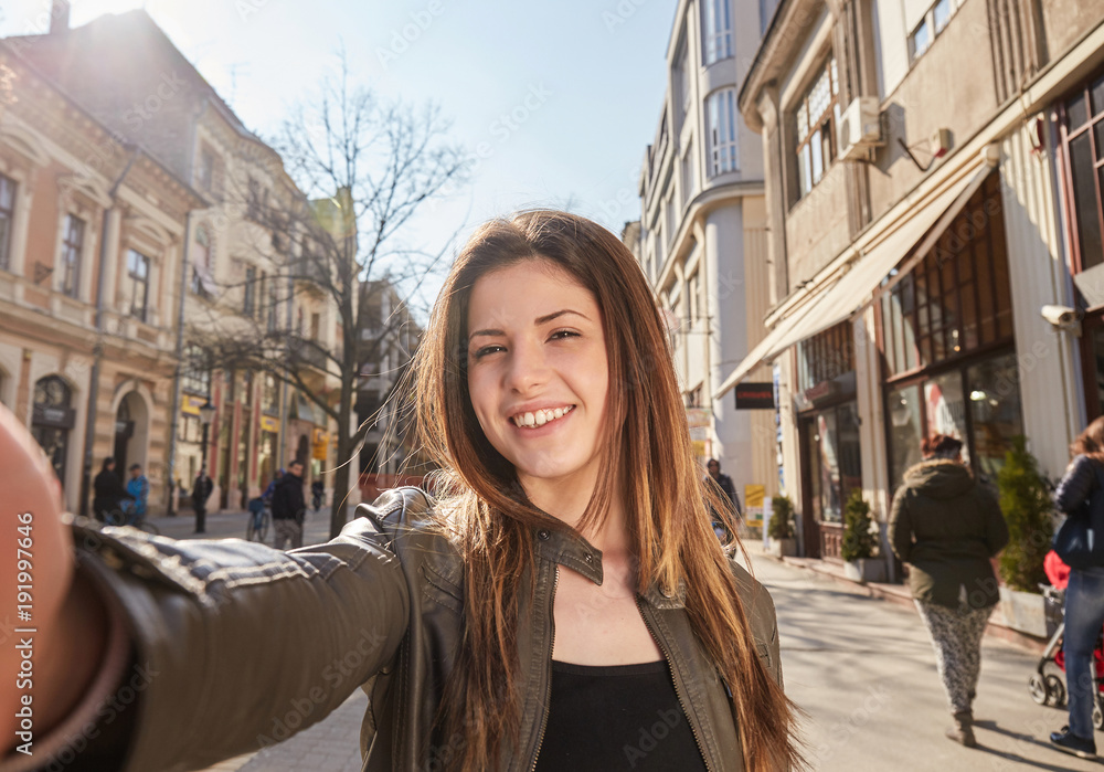 young girl make a selfy on the street in spring