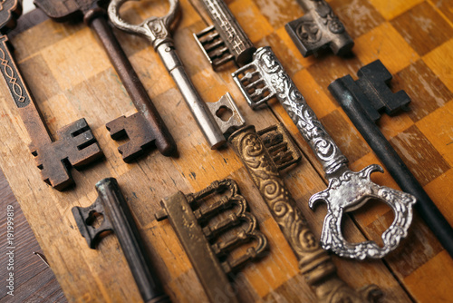 Many different vintage keys on a wooden background