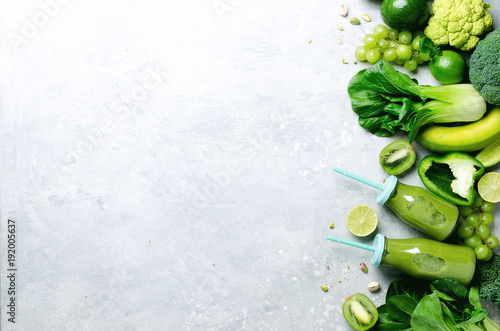 Fotografie Green smoothie in glass jar with fresh organic green vegetables and fruits on grey background