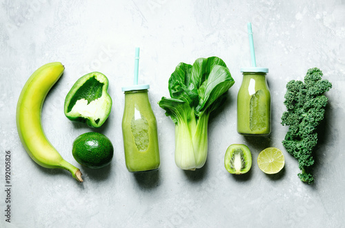 Fotografie Green smoothie in glass jar with fresh organic green vegetables and fruits on grey background