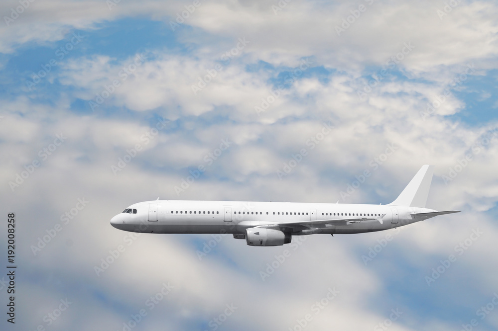 Obraz premium The white passenger plane flies against a slightly cloudy sky