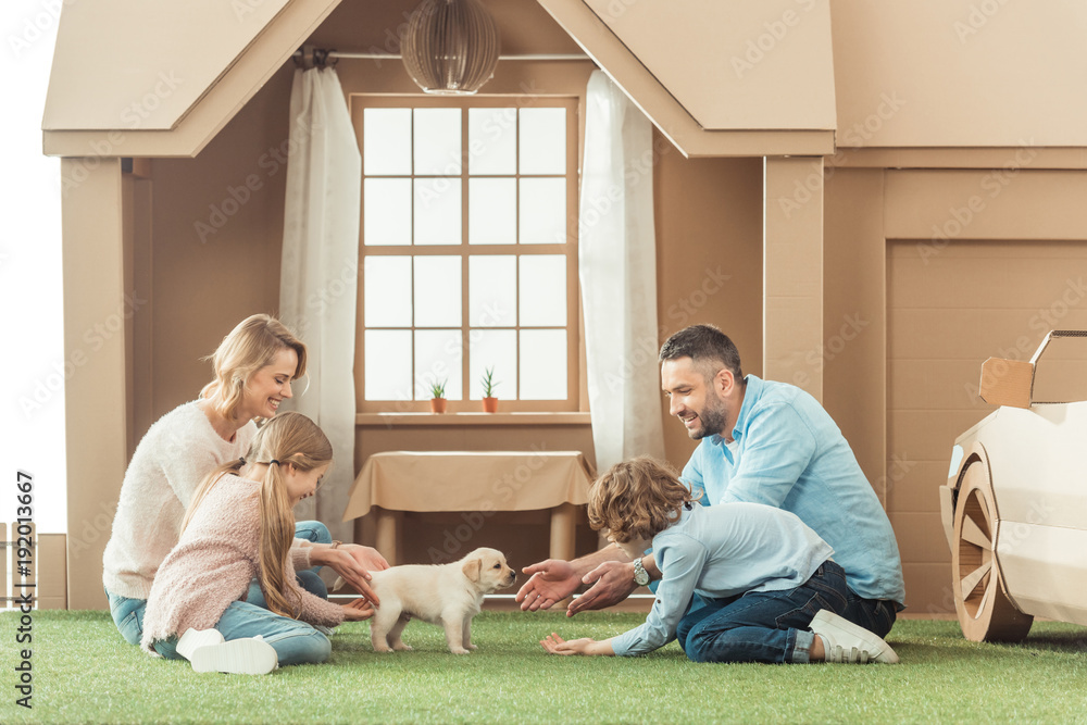 Φωτογραφία happy family with adorable puppy on yard of cardboard house