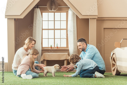 happy family with adorable puppy on yard of cardboard house