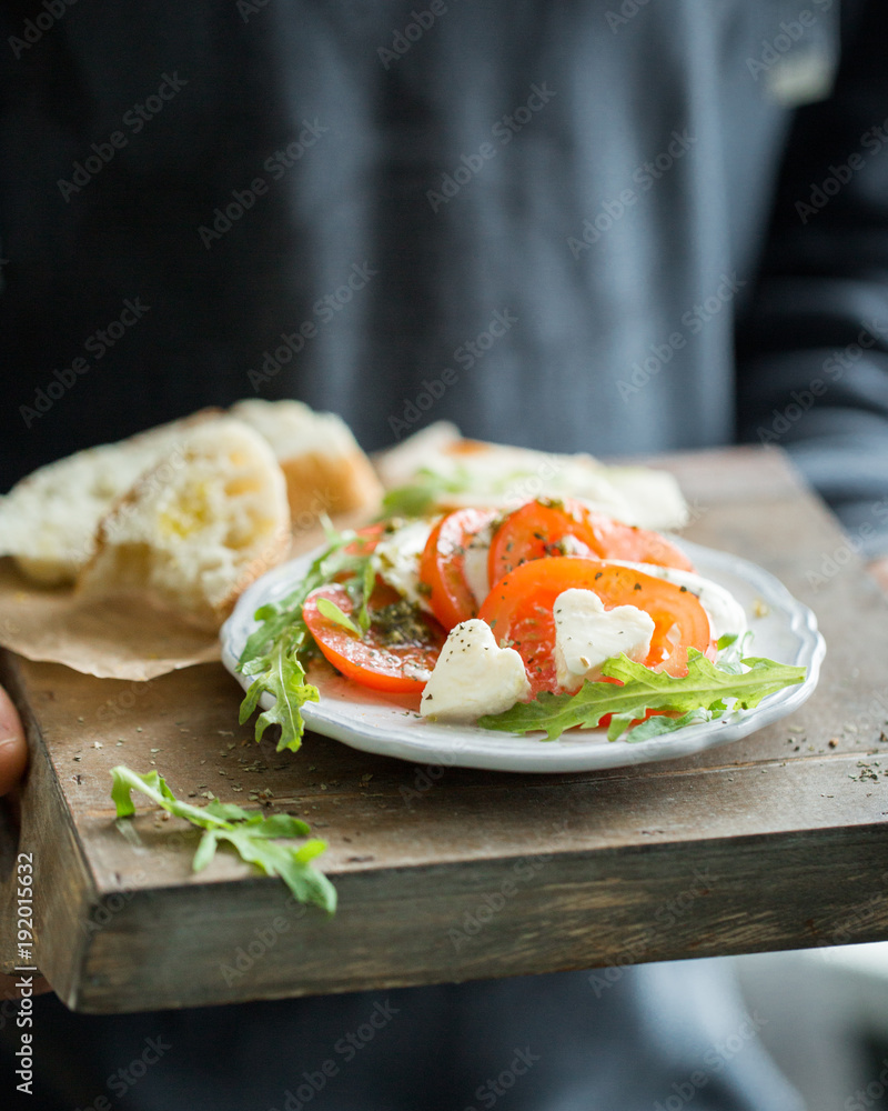 Φωτογραφία Hearts of sliced Italian cheese Mozzarella with a fresh arugula, tomatoes, olive oil, pesto sauce and bread toasts on a wooden box