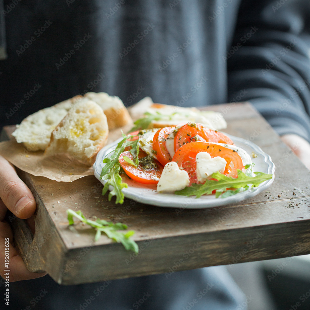 Φωτογραφία Hearts of sliced Italian cheese Mozzarella with a fresh arugula, tomatoes, olive oil, pesto sauce and bread toasts on a wooden box
