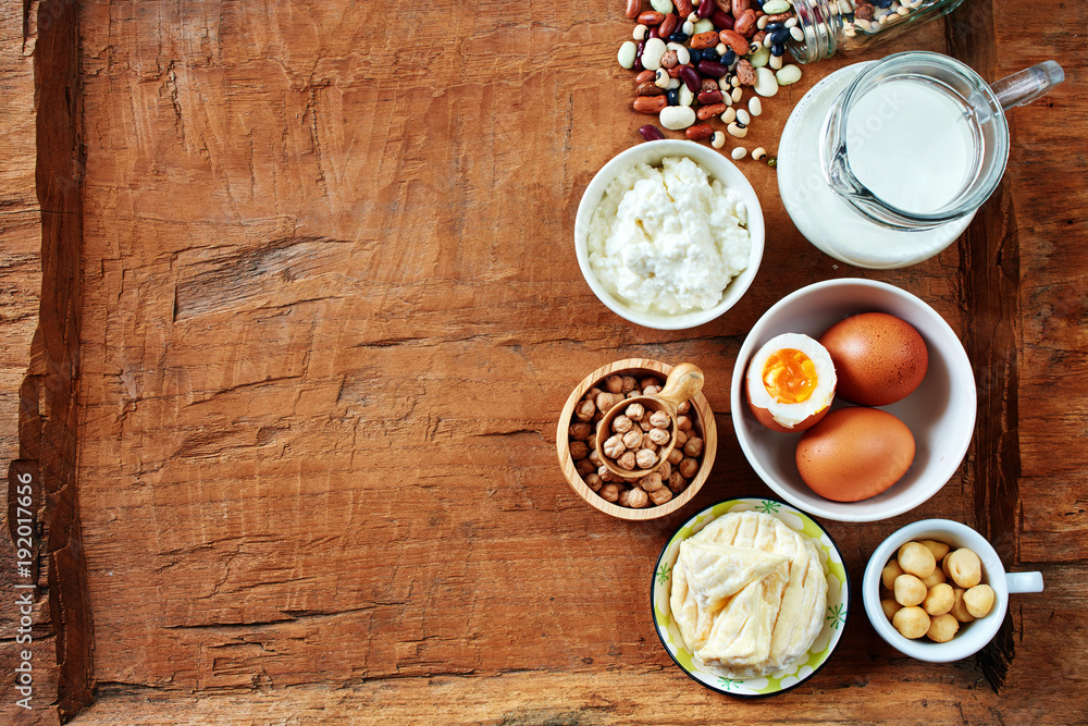 Flat lay of high-protein foods over rustic backgroung with copy space. Cottage cheese, milk, eggs, chickpea, nuts and beans. Flat lay of high-protein foods over rustic backgroung with copy space. Cottage cheese, milk, eggs, chickpea, nuts and beans.