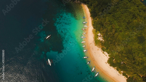Beautiful beach with boats and tourists. Tropical bay in El Nido. Aerial view: bay and the tropical island. Tropical lagoon with turquoise water and white sand. Seascape: mountains, ocean. Sky and