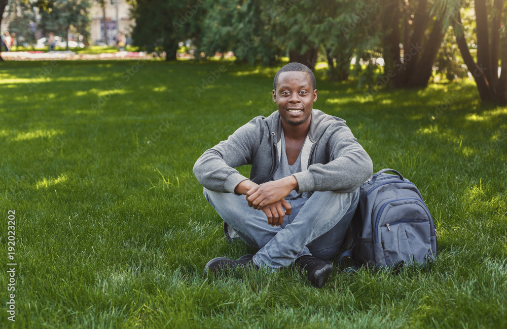 Happy african-american student sitting in university campus outdoors Happy african-american student sitting in university campus outdoors