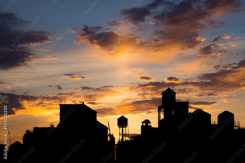 Silhouetted rooftops and water towers at sunset Silhouetted rooftops and water towers at sunset