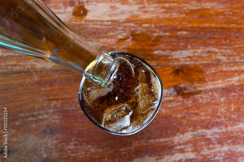 A glass of cola with ice on old wood textured