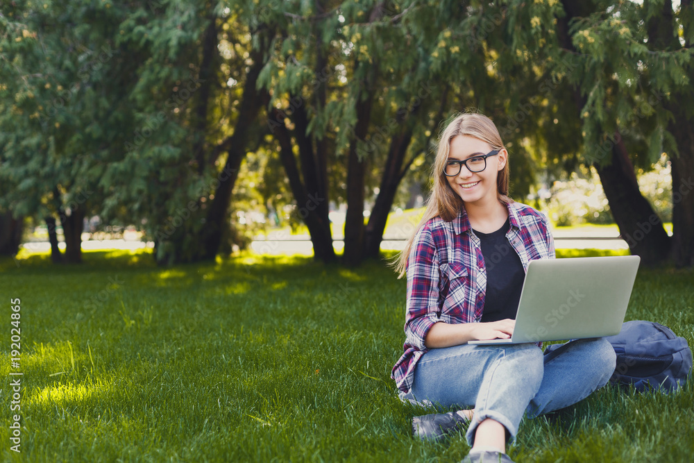 Happy young woman using laptop in park Happy young woman using laptop in park