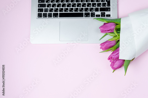 Fototapeta Naklejka Na Ścianę i Meble -  Woman desktop with Laptop, morning coffee and tulips on violet background. Flat lay, Spring holiday. Mother day