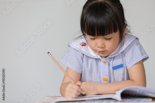 Little asian kid at home doing homework.