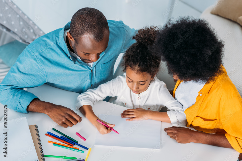 Naklejka premium high angle view of african american parents looking at daughter paint at home