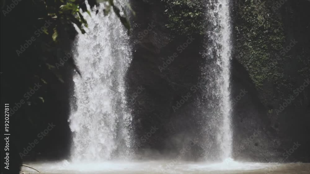 Bali Waterfall , water goind down with huge power in slowmotion, waterfall around the wild green jungle after rain in forest in sunny summerday. Bali Waterfall , water goind down with huge power in slowmotion, waterfall around the wild green jungle after rain in forest in sunny summerday.