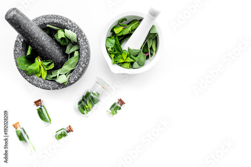 Phytotherapy. Herbs in mortar bowl and in small glasses on white background top view copy space