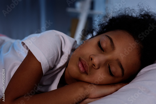 adorable african american kid sleeping in bed at home