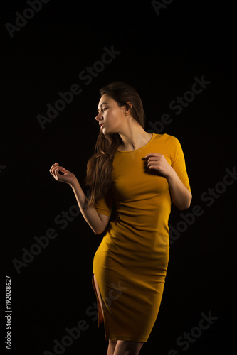 Amazing young woman with long hair posing in yellow dress in the shadow