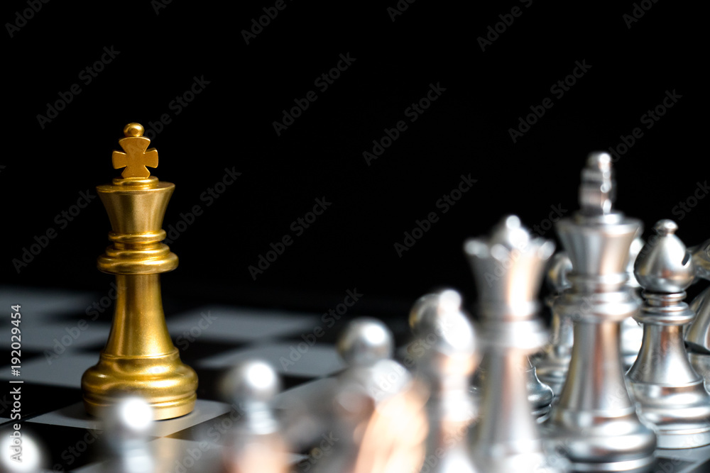Gold King in chess game face with the another silver team on black background (Concept for company strategy, business victory or decision) Gold King in chess game face with the another silver team on black background (Concept for company strategy, business victory or decision)