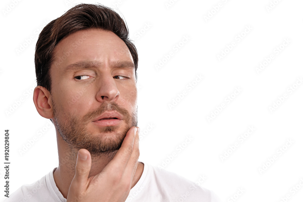 Handsome bearded man cares about his clean healthy skin is isolated on a white background. Guy touches his face with concerned thoughts Handsome bearded man cares about his clean healthy skin is isolated on a white background. Guy touches his face with concerned thoughts