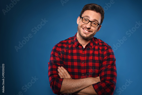 Handsome bearded man in glasses and red shirt Isolated on a dark blue background. Smart happy hipster is thinking and smiling