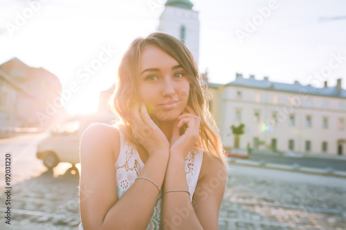 Lovely blonde woman with charming smile posing at the sunrise and sun glare