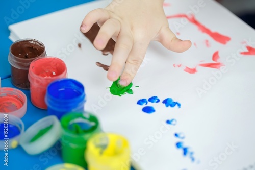 Cute girl shows dissapointment and sad emotions due to covered with paint hands and fingers