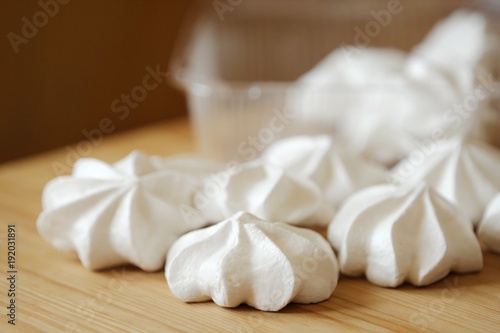 White fresh tasty meringues on wooden table 
