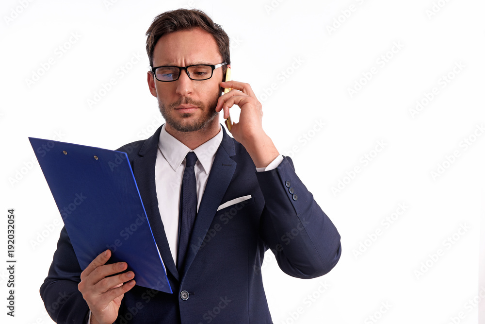 Handsome bearded businessman in office suit and tie isolated on white background. Professional bank manager is holding a blank clipboard while talking on a phone Handsome bearded businessman in office suit and tie isolated on white background. Professional bank manager is holding a blank clipboard while talking on a phone