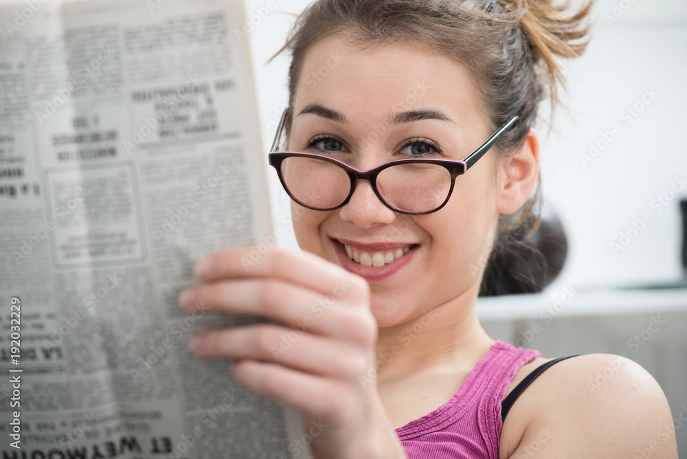 young and smiling woman with glasses, reading newspaper young and smiling woman with glasses, reading newspaper