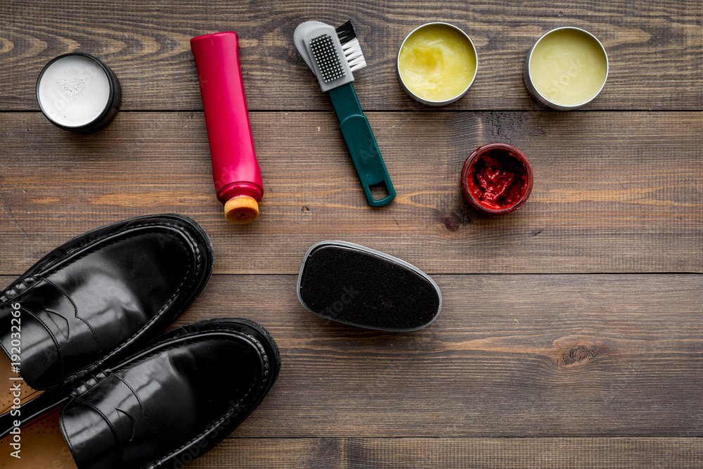 Shoe polish, brushes, wax near black shiny leather shoes on dark wooden background top view copy space Shoe polish, brushes, wax near black shiny leather shoes on dark wooden background top view copy space