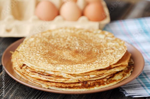 Fresh pancakes and eggs on a wooden table