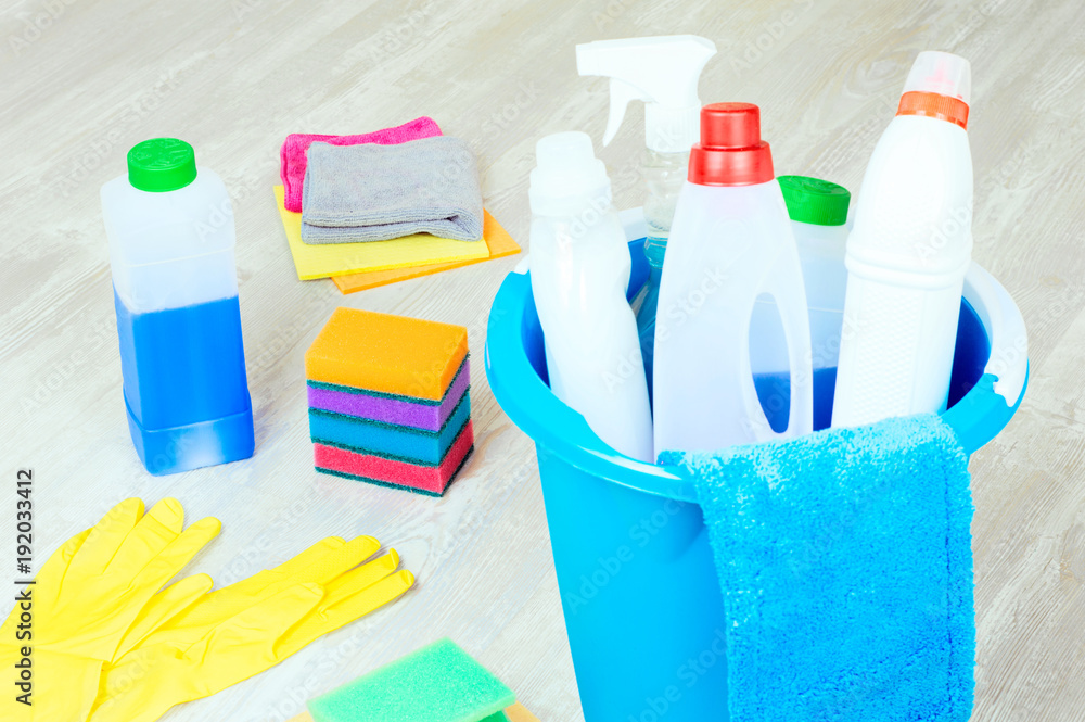 Basket with variety cleaning products on wooden floor. Cleaning and housekeeping concept Basket with variety cleaning products on wooden floor. Cleaning and housekeeping concept