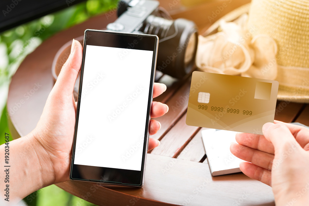 Obraz premium Woman hand holding a credit card and a smart phone in the coffee shop for a shopping on-line concept.