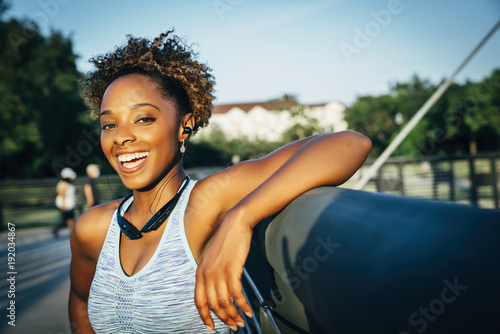 Smiling mixed race woman listening to earbuds on bridge photo