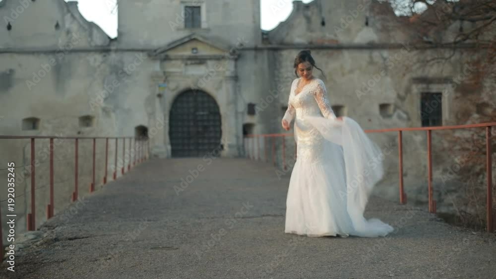 The beautiful bride standing on the bride near the old castle. Slow motion The beautiful bride standing on the bride near the old castle. Slow motion