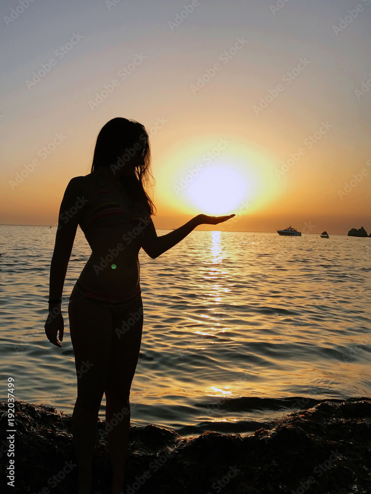 Sexy young woman silhouette in the sunset on the beach