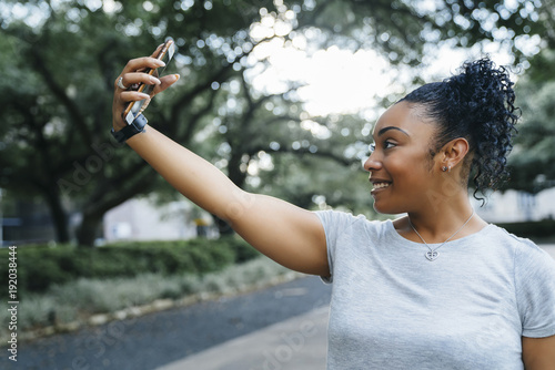 Smiling Black woman posing for cell phone selfie photo