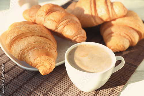 Delicious croissants with cup of coffee on table