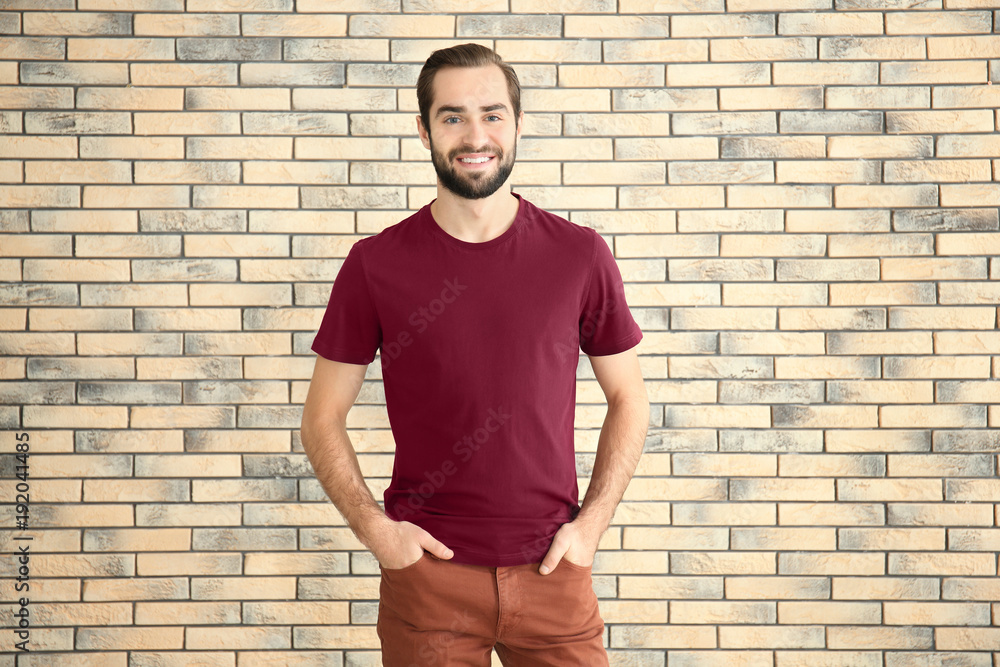 Young man in stylish t-shirt against brick wall. Mockup for design Young man in stylish t-shirt against brick wall. Mockup for design