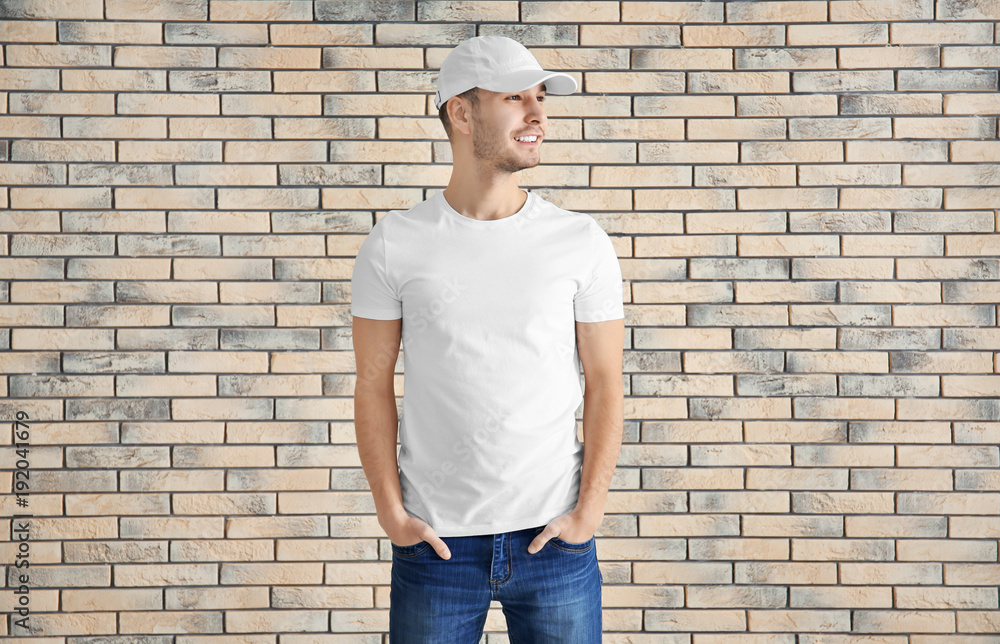 Young man in stylish t-shirt against brick wall. Mockup for design Young man in stylish t-shirt against brick wall. Mockup for design