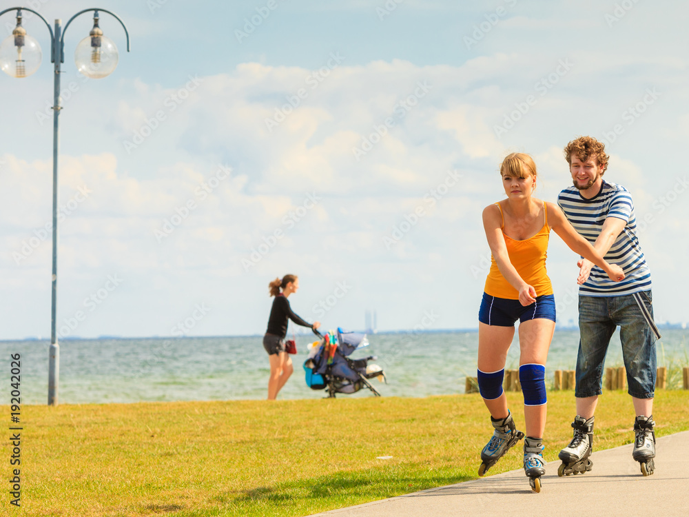 Fototapeta premium Young couple on roller skates riding outdoors