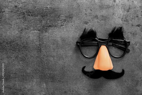 Funny glasses on grey background. April fool's day celebration