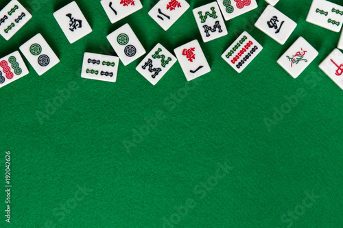 White-green tiles for mahjong on on green cloth background. Emty space from below