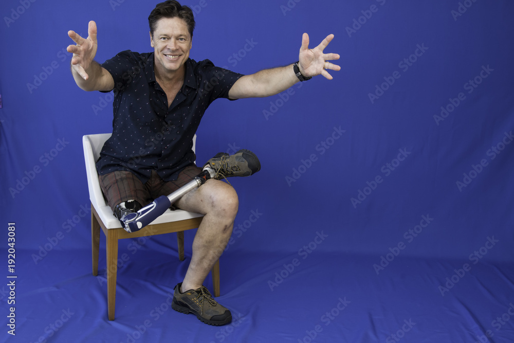 Obraz premium Middle-aged man with physical disability, happy with life sitting on the chair