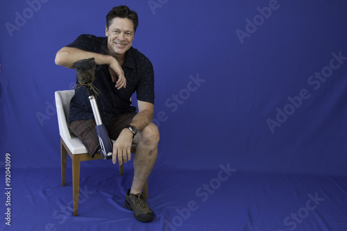 Middle-aged man with physical disability, happy with life sitting on the chair